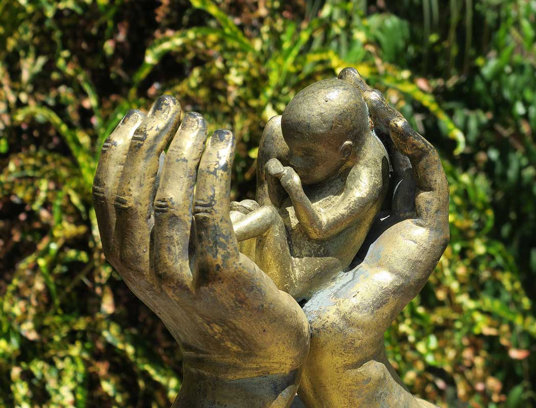 Statue eines von Händen geschütztes Ungeborenes